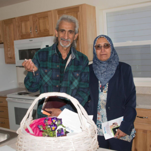 A couple standing in a kitchen with house keys.