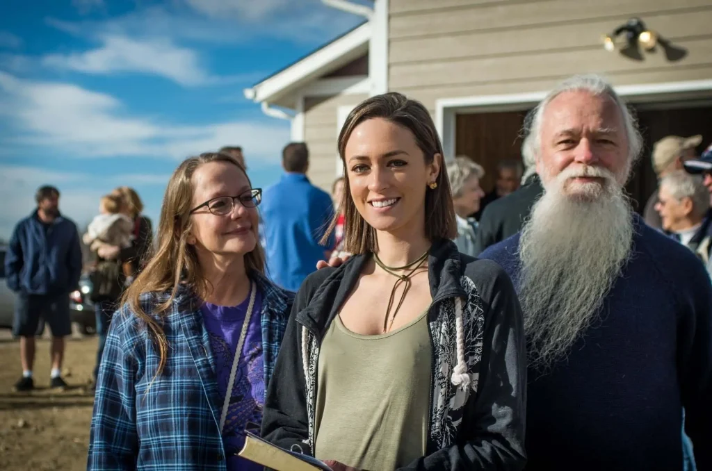 Nikkole and her parents in front of her home.