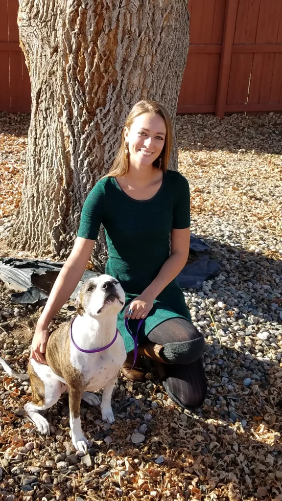 Nikkole and her dog in front of a tree.