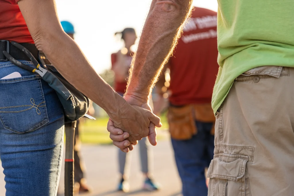 Two people's hands clasped, photographed from behind.