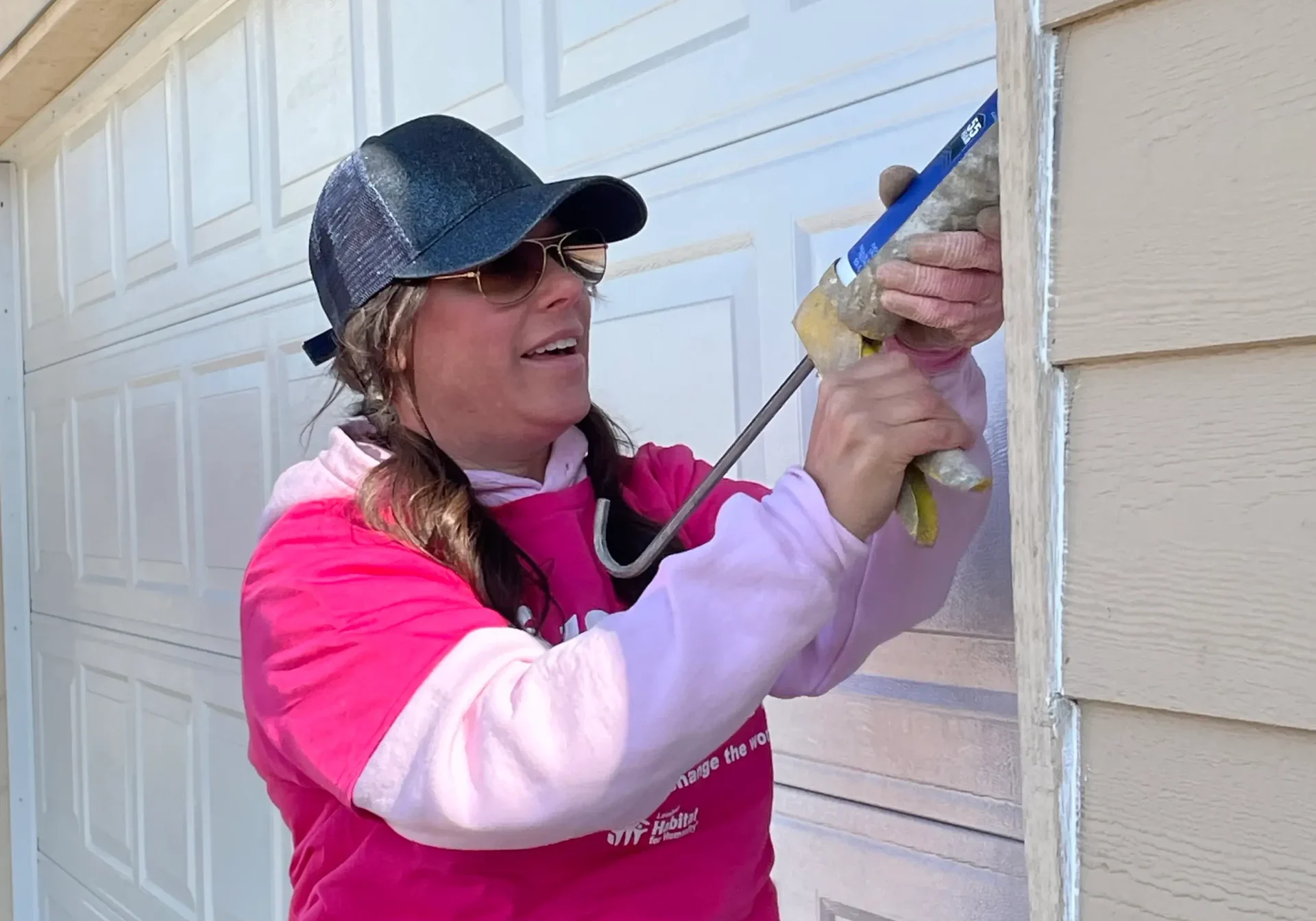 A woman caulking a garage door. A woman caulking a garage door.