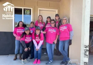 Group of women in Women Build shirts in front of a home