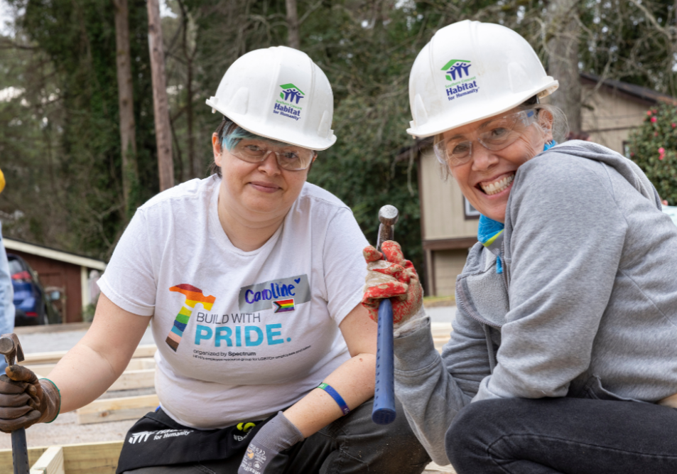 pridebuild6 Two people in hard hats smiling at the camera.