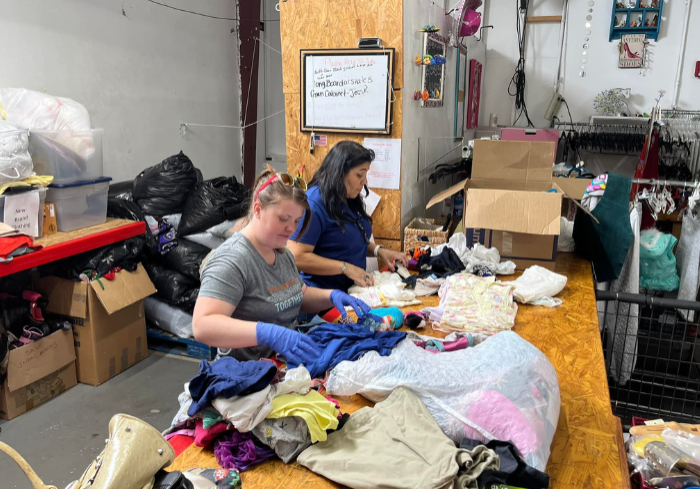 restore volunteer Two volunteers sorting donated clothing.